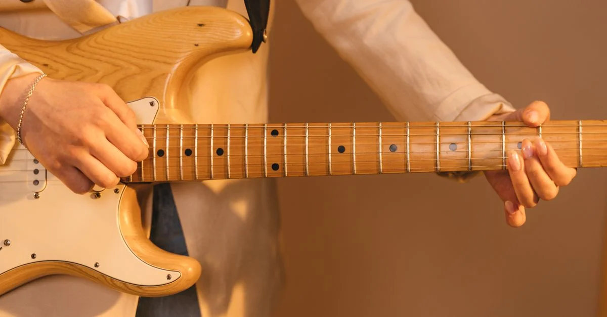 Un gros plan détaillé des mains grattant une guitare électrique, montrant la technique.