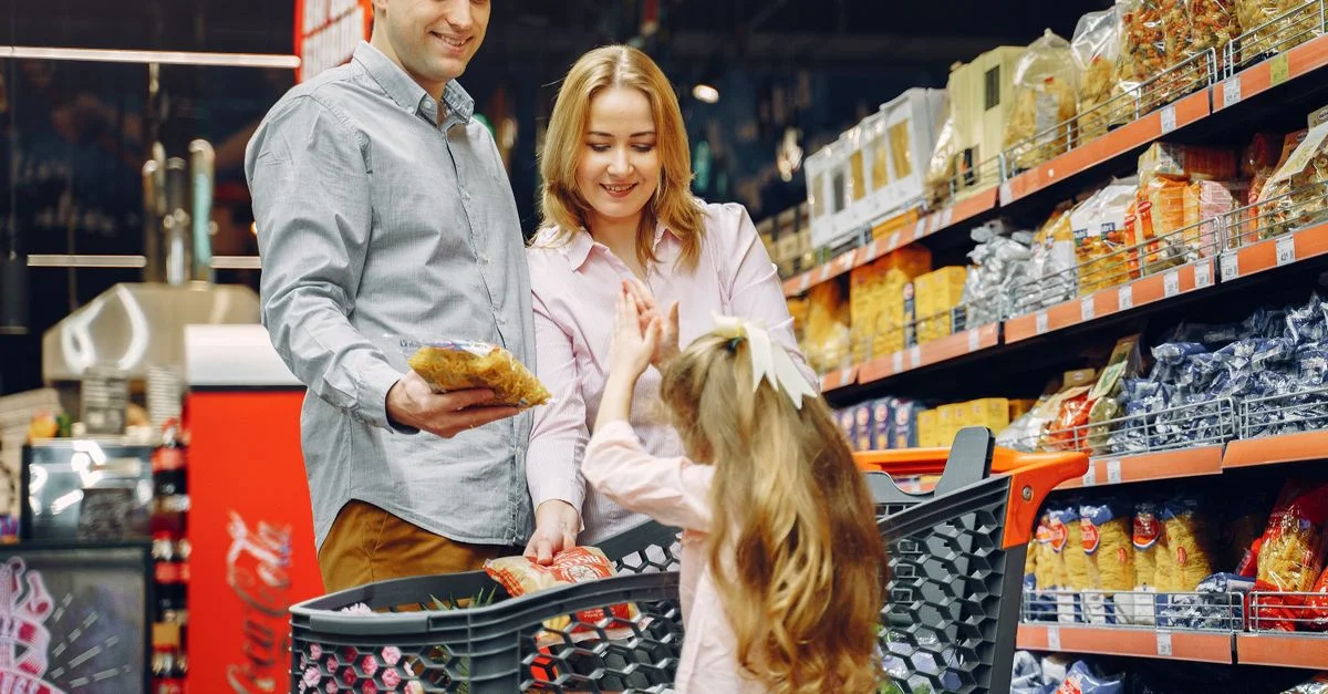 Une famille heureuse faisant des courses ensemble dans un rayon de supermarché, partageant un moment de joie.