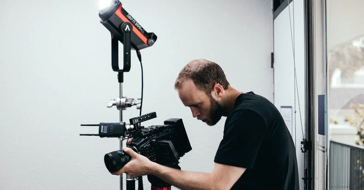 Caméraman préparant un appareil photo professionnel et un éclairage dans un studio.