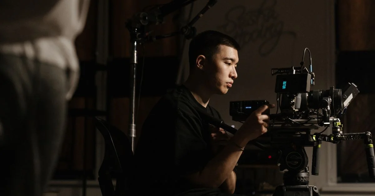 Vue de côté d'un cameraman utilisant un équipement professionnel pendant une production cinématographique en intérieur.