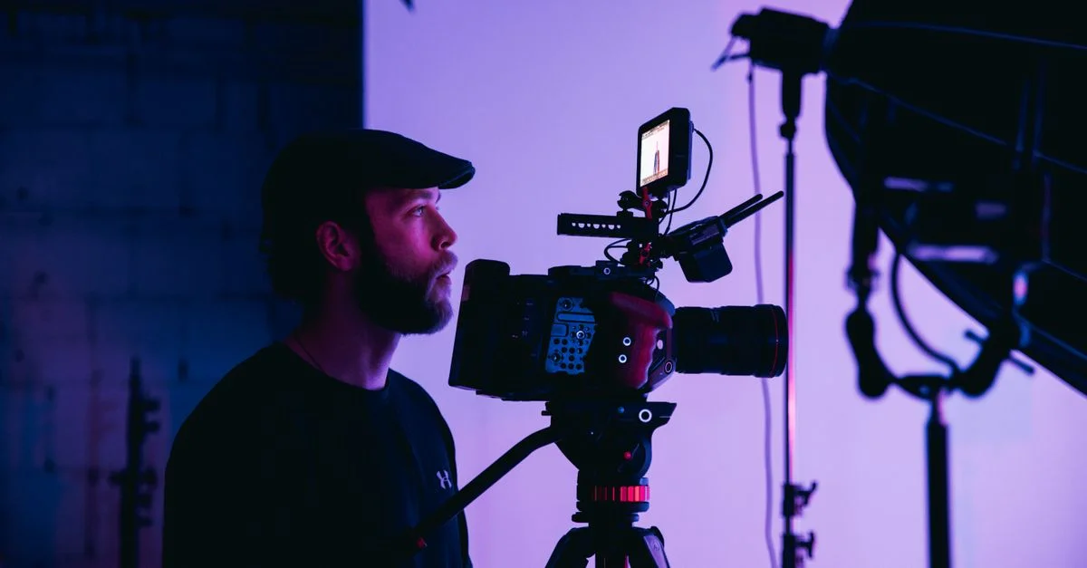 Le cinéaste se concentre intensément sur le réglage de la caméra pour une séance photo en studio.