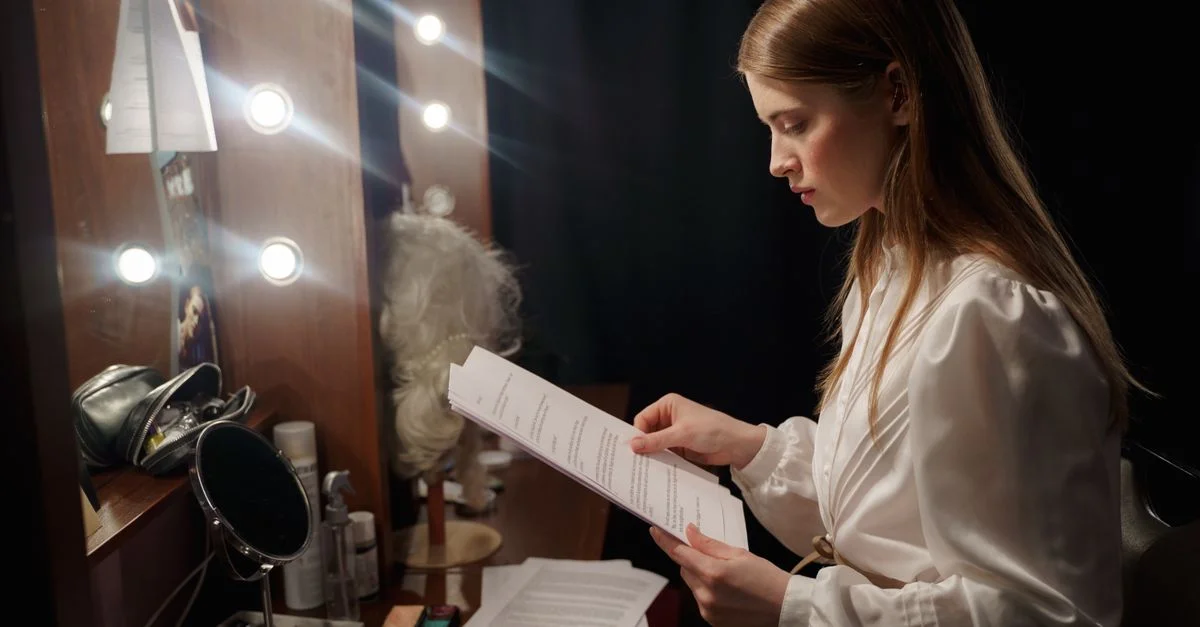 Une actrice consulte son scénario dans un cadre de dressing glamour, pleine d'anticipation.