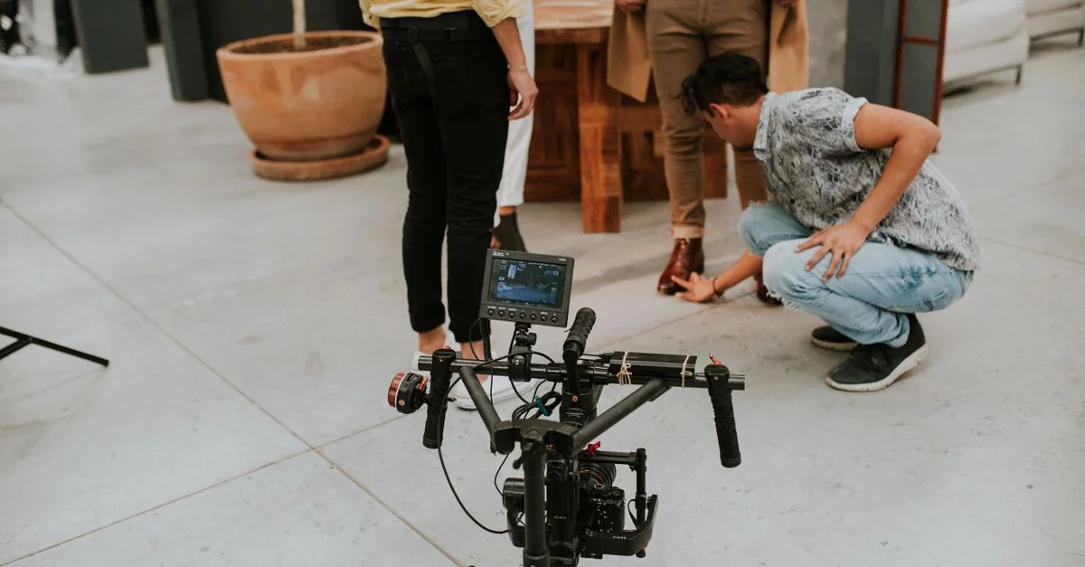 Équipe de tournage ajustant les réglages sur un plateau de cinéma intérieur. Caméra et personnes impliquées.