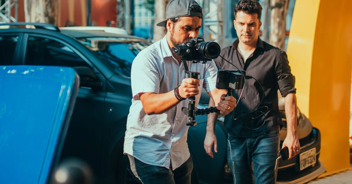 Deux hommes gérant un tournage avec un stabilisateur de caméra en extérieur, montrant une gestion professionnelle du matériel.